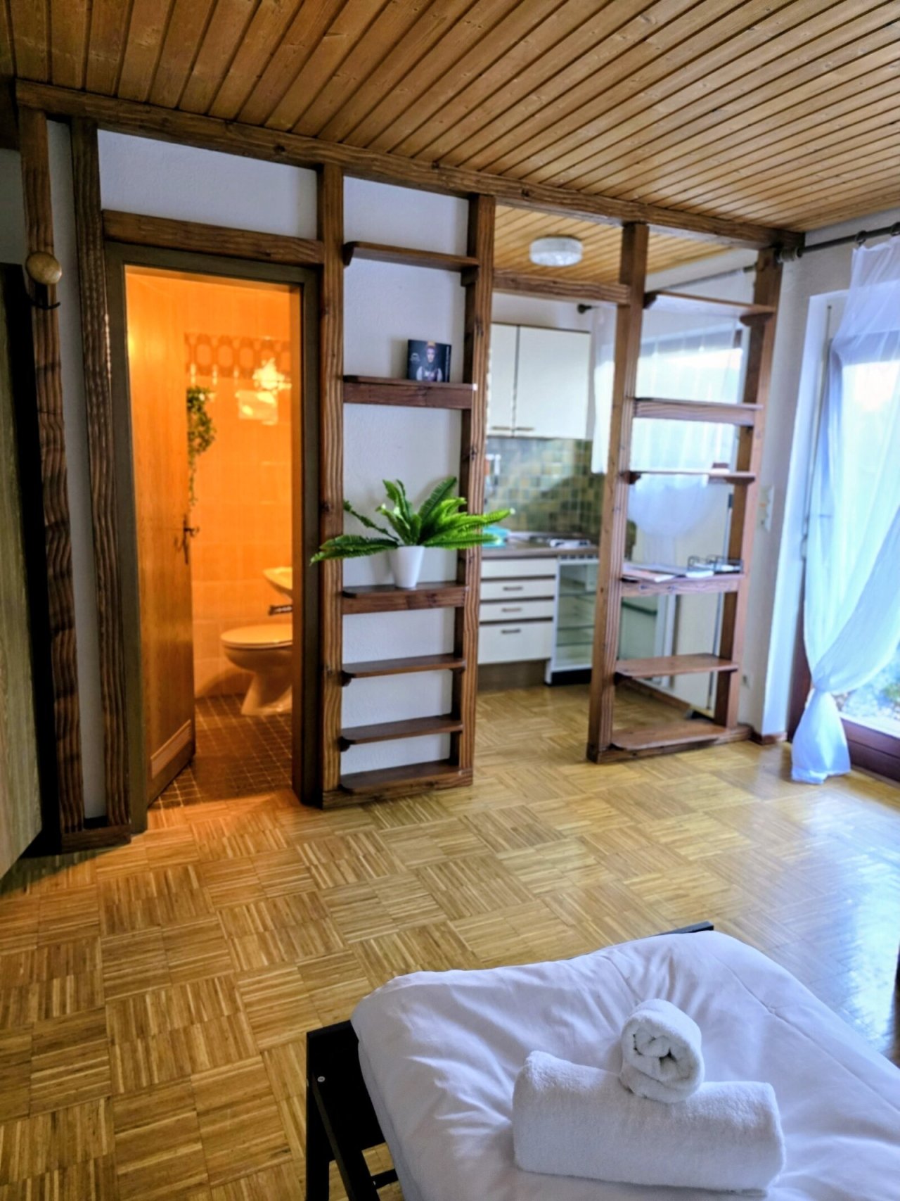 Loft-Charme mit intelligenter Raumteilung: Offene Wohnküche mit stylishem Holzständerwerk und integriertem Badezugang