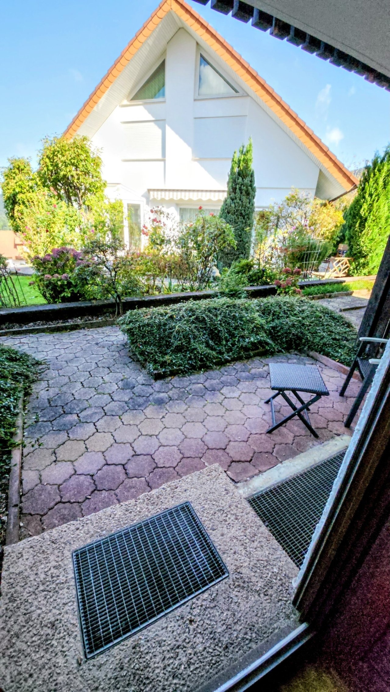Idyllische Terrasse mit Natursteinpflaster - Ihr privates Gartenparadies mit charmantem Einfamilienhaus im Hintergrund
